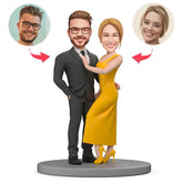 בובה זוגית בהתאמה אישית בהשראת לוק הוליוודי – גבר בחליפה שחורה ואישה בשמלה צהובה אלגנטית עומדים מחובקים על במה עגולה.